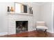 Living room features a traditional fireplace with painted brick and updated mantle and modern chair at 206 Bickett Blvd, Raleigh, NC 27608