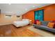 Comfortable bedroom with hardwood floors, natural light, and a gray loveseat with colorful pillows at 211 Hargrove St St, Durham, NC 27701