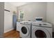 Bright laundry room features a stacked washer and dryer set, wash sink, and hardwood floors at 211 Hargrove St St, Durham, NC 27701