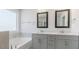Bright bathroom features double vanity, framed mirrors, and a soaking tub under a large window at 2322 Sugar Cone Way, Fuquay Varina, NC 27526