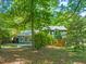 Home's back exterior features a wood deck and large windows, surrounded by mature trees at 2417 Lawrence Dr, Raleigh, NC 27603