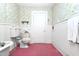 Traditional bathroom with a vintage toilet, floral wallpaper, and a door at 305 N Ellis Ave, Dunn, NC 28334