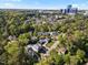Wide aerial view showcasing a neighborhood surrounded by lush green trees and cityscape in distance at 3513 Bellevue Rd, Raleigh, NC 27609