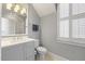 Well-lit bathroom featuring a gray vanity, toilet, and plantation shutters at 3513 Bellevue Rd, Raleigh, NC 27609