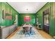 Formal dining room with green accent wall, hardwood floors, and stylish chandelier at 3513 Bellevue Rd, Raleigh, NC 27609