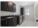 Modern laundry room with dark cabinetry, countertops, a sink, and stainless steel washer and dryer at 3513 Bellevue Rd, Raleigh, NC 27609