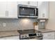 Bright kitchen boasts stainless steel appliances, white cabinets, and stylish backsplash at 4304 S Greg Allen Way, Oxford, NC 27565