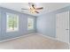 Blue bedroom with ceiling fan, two windows, carpet, and white door at 5424 Westminster Ln, Fuquay Varina, NC 27526