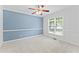 Bright bedroom with a blue accent wall, plush carpet, large window with natural light, and modern ceiling fan at 5424 Westminster Ln, Fuquay Varina, NC 27526