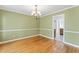 Dining room featuring hardwood floors, elegant chandelier, and soft green walls with white trim at 5424 Westminster Ln, Fuquay Varina, NC 27526