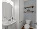 Stylish powder room featuring unique wallpaper, floating shelves, and a pedestal sink at 5702 Cameo Glass Way, Raleigh, NC 27612