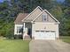 Inviting home featuring a two-car garage, well-manicured lawn, and mature landscaping at 66 Saddle Ln, Lillington, NC 27546