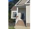 Elegant home entrance with brick steps, white railing, and a decorative front door at 66 Saddle Ln, Lillington, NC 27546