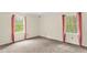 A bedroom featuring carpet, two windows with pink curtains, and neutral walls at 6702 Huntsboro Rd, Oxford, NC 27565
