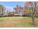 Serene view of a single-story brick home surrounded by lush greenery and flowering trees at 6702 Huntsboro Rd, Oxford, NC 27565