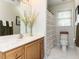 Well-lit bathroom with white tile, wood vanity, and striped shower curtain at 6909 Clear Sailing Ln, Raleigh, NC 27615
