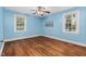 Light-filled bedroom features hardwood floors, two windows, and blue walls at 7110 Hunter Hill Rd, Rocky Mount, NC 27804