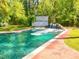 Sparkling backyard swimming pool with waterfall feature, adjacent pool house and a lush, green lawn at 7110 Hunter Hill Rd, Rocky Mount, NC 27804