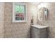 Charming powder room with decorative wallpaper, an oval mirror, and a window view of lush greenery at 7409 Fiesta Way, Raleigh, NC 27615