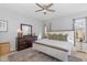 Sunlit bedroom featuring a ceiling fan, white and wood bedframe and a dark wood dresser with mirror at 756 Rockville Rd, Wake Forest, NC 27587