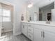 Clean bathroom featuring double sinks, white cabinetry, and a large mirror and doorway leading to another room at 781 Cormiche Ln, Wake Forest, NC 27587