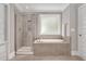 Modern bathroom featuring a glass enclosed shower and a built-in tub beneath a frosted glass window at 8016 Parker Mill Trl, Fuquay Varina, NC 27526