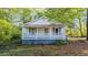Charming home featuring a cozy front porch with white railings and blue accents, surrounded by lush greenery at 8175 Nc 27 E, Coats, NC 27521