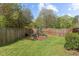 Backyard boasts a charming playground, wood fence, and mature trees, perfect for Gathering fun and outdoor adventures at 8812 Forester Ln, Apex, NC 27539