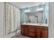 Bathroom featuring dual sinks, wooden cabinets, and a shower-tub combination with floral curtain at 8812 Forester Ln, Apex, NC 27539