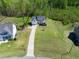 An aerial view of a two-story, light colored home with a driveway surrounded by lush green grass and trees at 9220 Yardley Town Dr, Wake Forest, NC 27587
