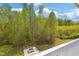 A backyard view from the deck, showcasing a brick fire pit surrounded by green grass and trees at 9220 Yardley Town Dr, Wake Forest, NC 27587