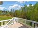 View from the wooden deck with white railings overlooking a grassy lawn and a lush green forest at 9220 Yardley Town Dr, Wake Forest, NC 27587