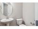 Powder room with round mirror, pedestal sink, and white fixtures at 9220 Yardley Town Dr, Wake Forest, NC 27587