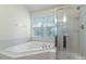 Bathroom with a large bathtub, shower, and a window at 9531 Vira Dr, Raleigh, NC 27617