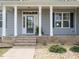 Covered front porch features classic white columns and a modern glass-paneled front door and low maintenance landscaping at 96 Ada Cir, Selma, NC 27576