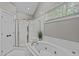 Bright bathroom featuring vaulted ceiling, jacuzzi tub, a window, and glass-enclosed shower for a clean and modern look at 102 Parkbranch Ln, Cary, NC 27519