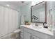 Well-lit bathroom featuring a shower, a decorative mirror, and vanity with white cabinets at 1126 Russet Ln, Apex, NC 27523