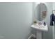 Stylish powder room featuring a pedestal sink, round mirror, and modern fixtures at 1126 Russet Ln, Apex, NC 27523