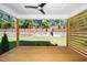 View of the outdoor deck featuring a ceiling fan, wooden posts, and a backyard with a stone wall at 1207 Chaney Rd, Raleigh, NC 27606
