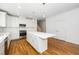 Open concept kitchen featuring white cabinets, an island, hardwood floors, and stainless steel appliances at 1207 Chaney Rd, Raleigh, NC 27606