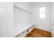 Bright mud room featuring a white bench, hooks, shelving, hardwood floors and a single window at 1207 Chaney Rd, Raleigh, NC 27606