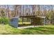 Picture shows a detached metal carport with a concrete pad, nestled in a lush, grassy landscape with trees in the background at 13832 Nc 96 N Hwy, Zebulon, NC 27597