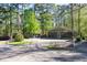 Exterior view of a green home in a wooded area with gravel landscaping and street access at 142 Blackhawk Dr, Louisburg, NC 27549
