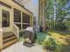 Patio with grill, steps to the screened in porch, and mature landscaping in a peaceful backyard setting at 1512 Piazzo Ct, Apex, NC 27502