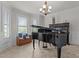 Bright living room with a piano, bay windows, neutral color palette and chandelier at 1512 Piazzo Ct, Apex, NC 27502