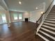 Open living room showcasing hardwood floors, a cozy fireplace, and stairs with a wooden railing at 1572 Bright Coral Trl, Wendell, NC 27591