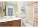 Well-lit bathroom features a wood vanity, shower and tub combo, and a window at 1914 Woodsdale Dr, Durham, NC 27703