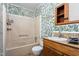 A full bathroom features patterned wallpaper, a bathtub with shower, and a vanity at 229 Watson Dr, Burlington, NC 27217
