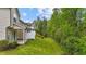 Backyard view with green grass, a privacy fence, covered patio, and mature trees alongside the townhome at 265 Mariah Towns Way, Garner, NC 27529