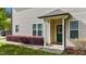 Inviting front entrance with lush landscaping, a covered porch, and stylish green door at 265 Mariah Towns Way, Garner, NC 27529